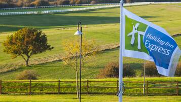 Located near a Holiday Inn Express, this serene field offers a peaceful escape with a tree and a wooden fence.