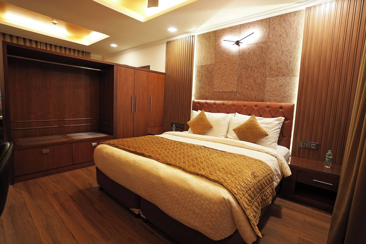 Un dormitorio amplio con una cama grande, un armario de madera y un ventilador de techo.
