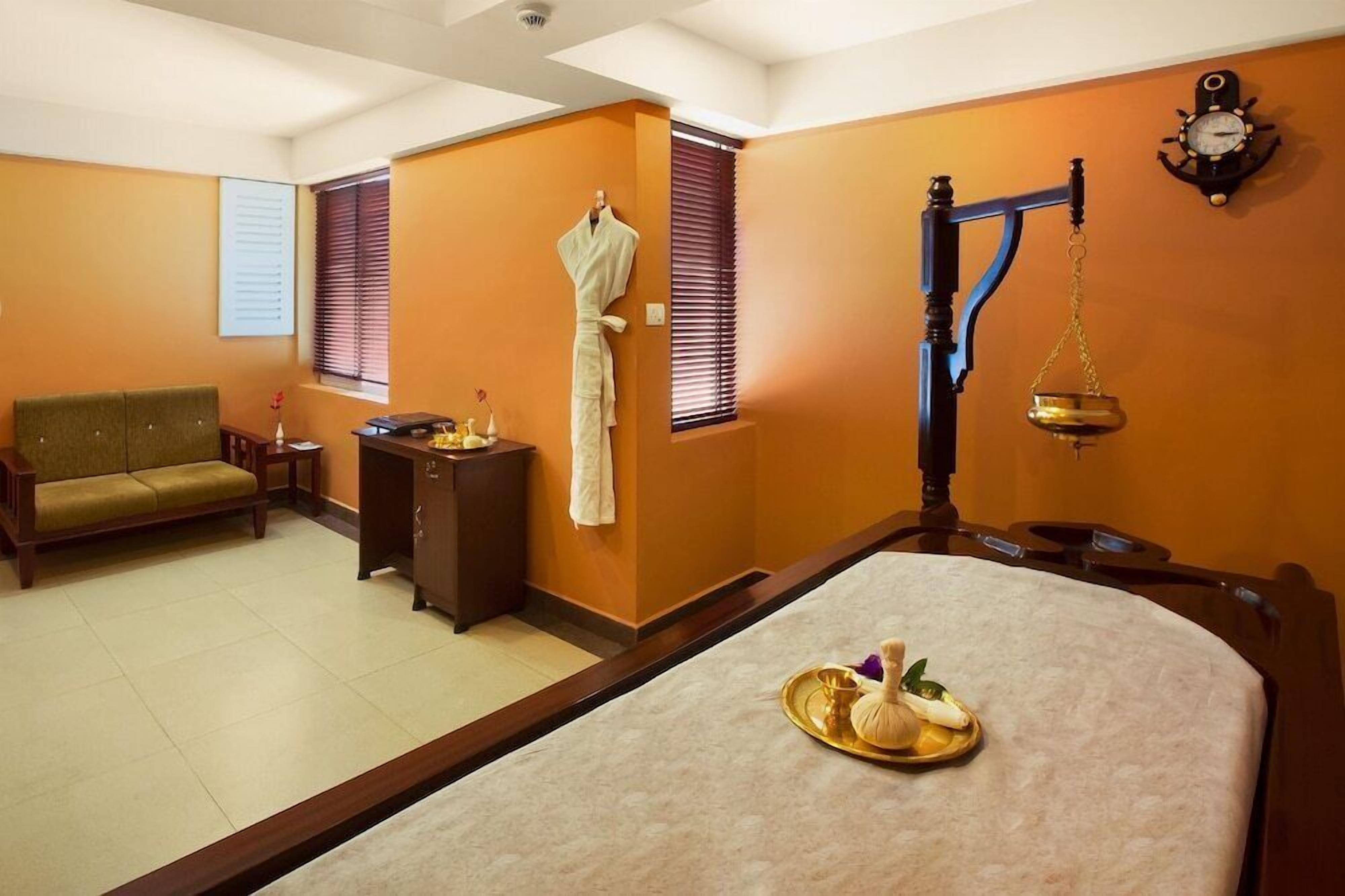 A room with a sofa, a small table with a tray of items, a scale, and a clock on the wall.