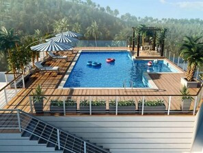 A rooftop pool with a wooden deck, lounge chairs, and umbrellas. - Thekkady - Woods n Spice (Peerumade)