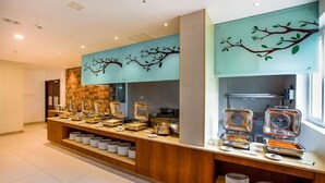 Un espace buffet proposant une variété de plats et un mur décoratif orné de branches d’arbres.