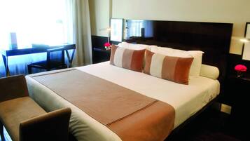 Una habitación de hotel con una cama grande, un escritorio y una silla.