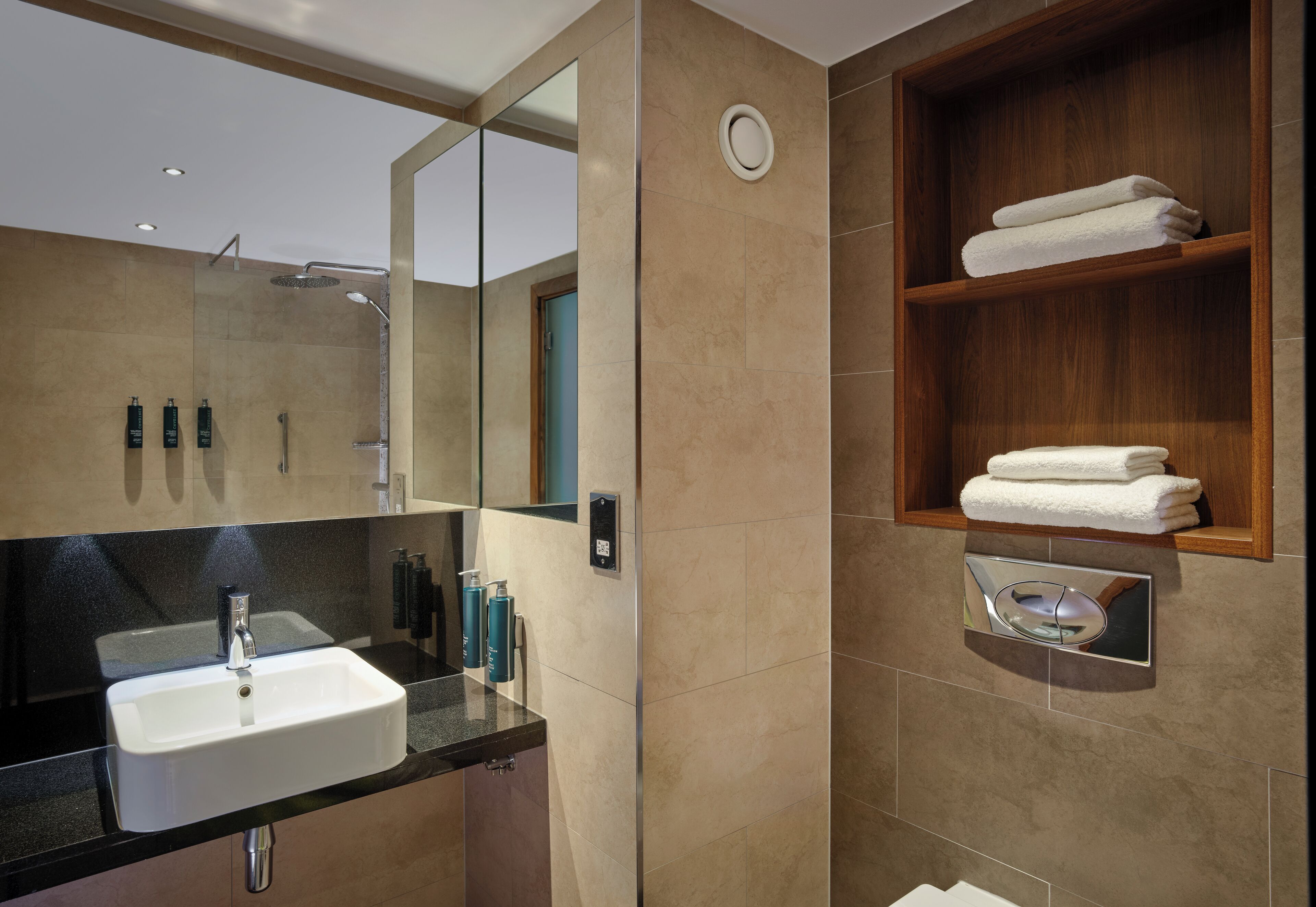 A modern bathroom with a sink, mirror, and wooden shelf with towels.