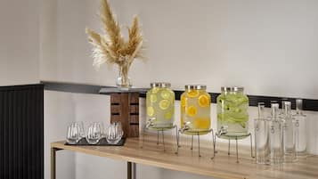 A bar area with a wooden table, clear glasses, and various glass containers with labels.