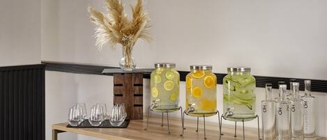A bar area with a wooden table, clear glasses, and various glass containers with labels.