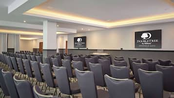 A conference room with rows of chairs, a podium, and a wall-mounted sign for DoubleTree by Hilton Sheffield City.