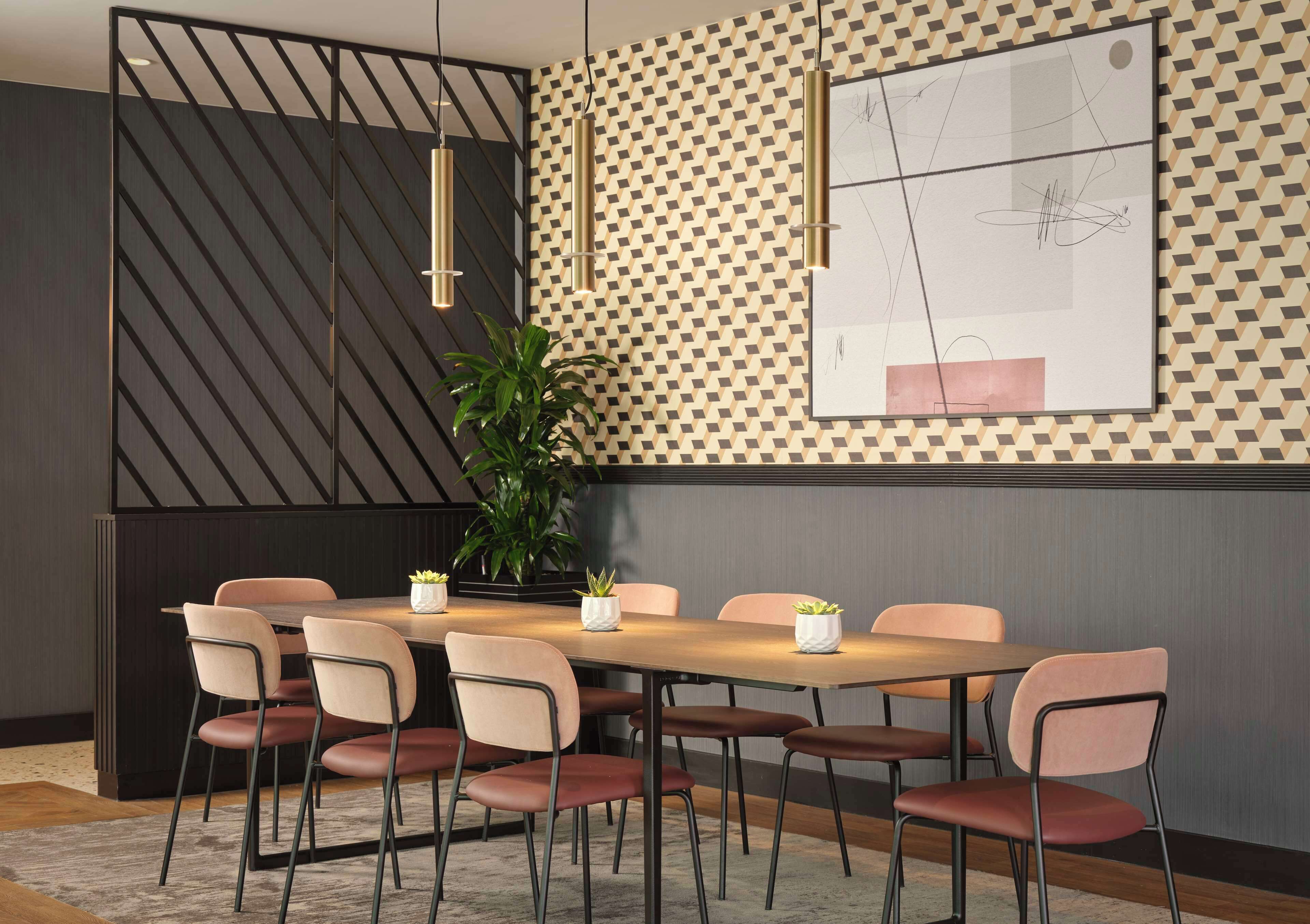 Un comedor moderno con una mesa de madera, seis sillas y lámparas colgantes.