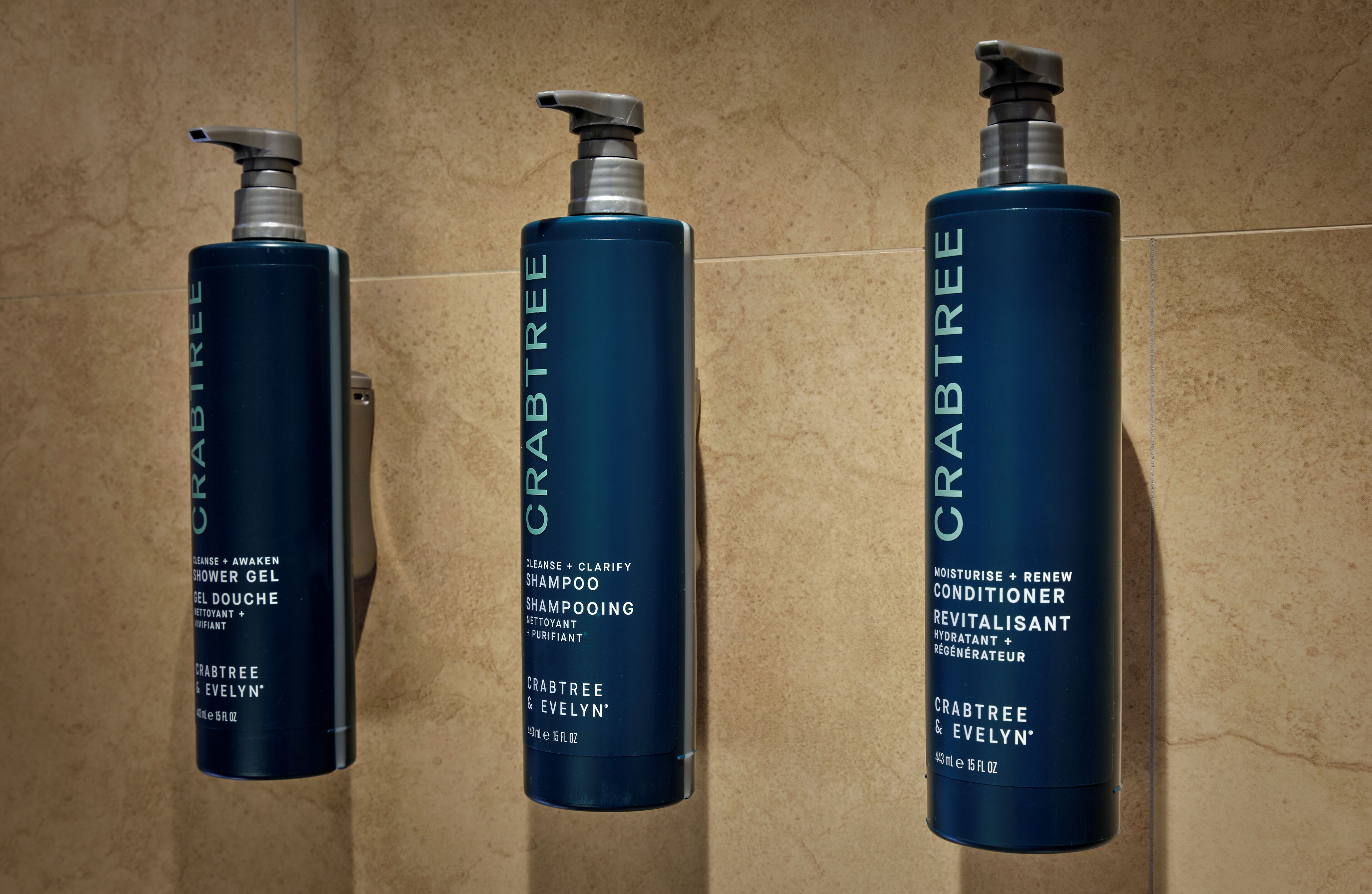 Three bottles of Crabtree & Evelyn hair care products on a tiled wall.