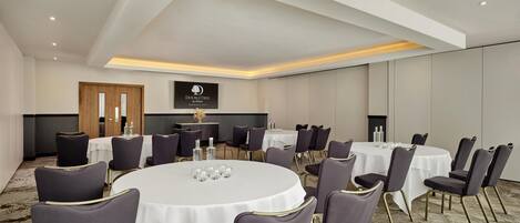 A conference room with round tables, chairs, and a 'DOUBLETREE by Hilton' sign on the wall.