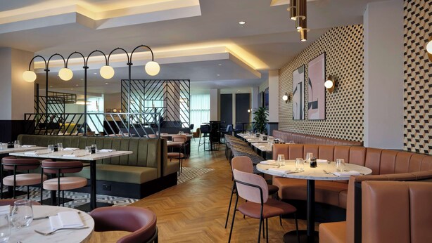 A modern restaurant with wooden flooring, leather booths, and a central dining area with tables and chairs. - DoubleTree by Hilton Sheffield City (Sheffield)