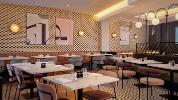 En restaurang med avskilda bås och bord, rutmönstrade väggar och hängande lampor.