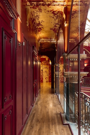 Stunning corridor with grand archway, lined with doors and a glass railing.