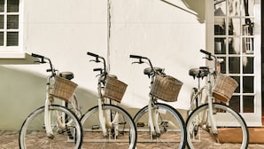 Three white bicycles with wicker baskets parked against a white wall. - Rosenhof Boutique Hotel (Oudtshoorn)