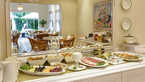 A buffet with various food items and a mirror reflecting a dining area. - Rosenhof Boutique Hotel (Oudtshoorn)