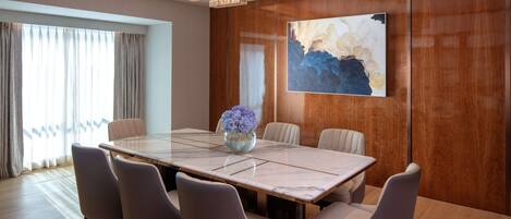A modern dining room with a marble table, six chairs, a chandelier, and a large abstract painting on the wall.