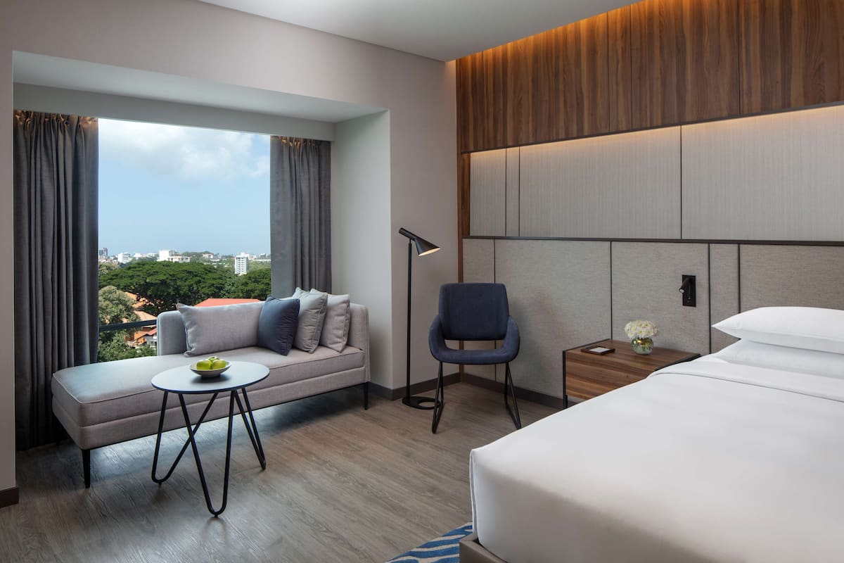 Une chambre d’hôtel moderne comprenant un canapé, une petite table, une chaise, une table de chevet avec une lampe et un grand lit.