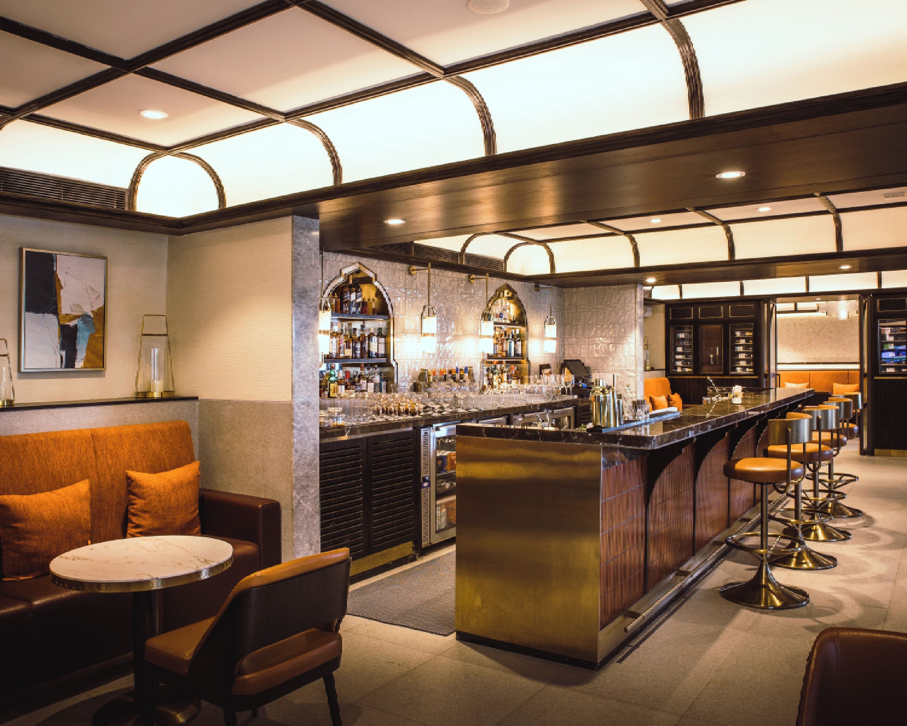 A bar area with a bar counter, stools, and a seating area with a couch and chairs.