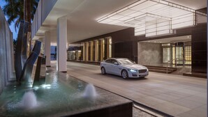 A modern building with a white car parked in front, a water feature, and a staircase leading to the entrance. - Hyatt Regency Trivandrum (Thiruvananthapuram)