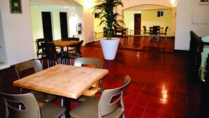 A spacious indoor area with a wooden table and chairs, a large potted plant, and a red-tiled floor. - Hotel Davimar (Guamuchil)