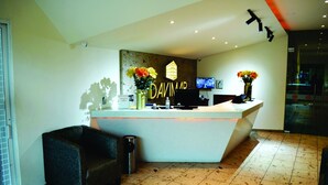 A reception desk with a modern design, a flat-screen TV, and decorative flowers. - Hotel Davimar (Guamuchil)