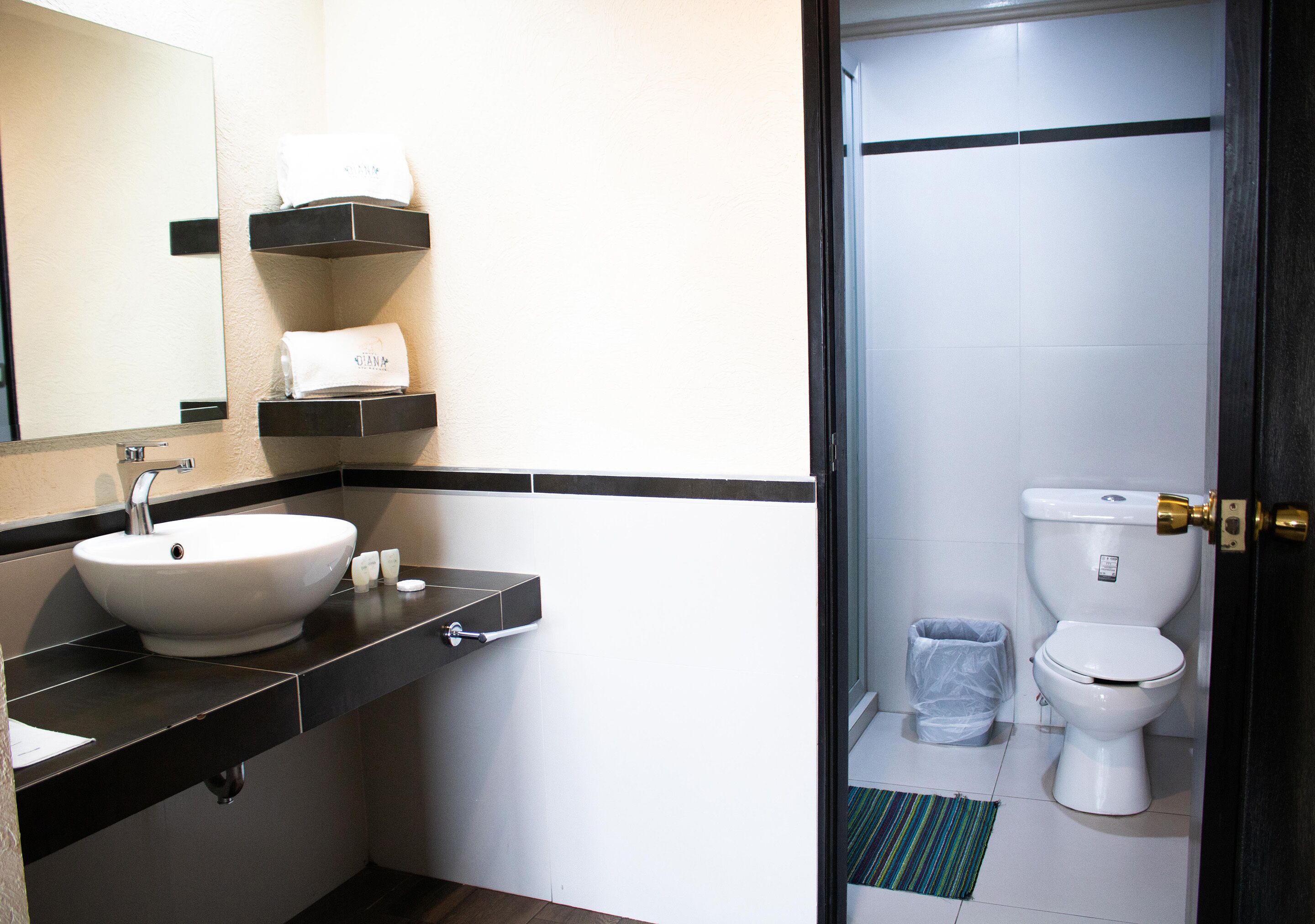 A modern bathroom with a white sink, black countertop, and a toilet.