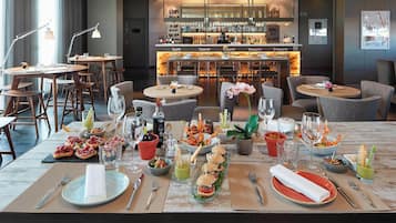 Un restaurante con barra, varias mesas para comer y una gran variedad de platos y bebidas.