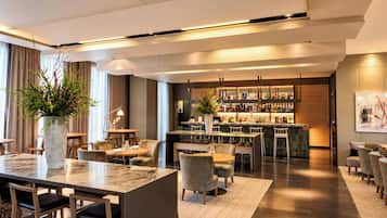 A modern hotel lobby with a bar area, seating arrangements, and a large vase with greenery.