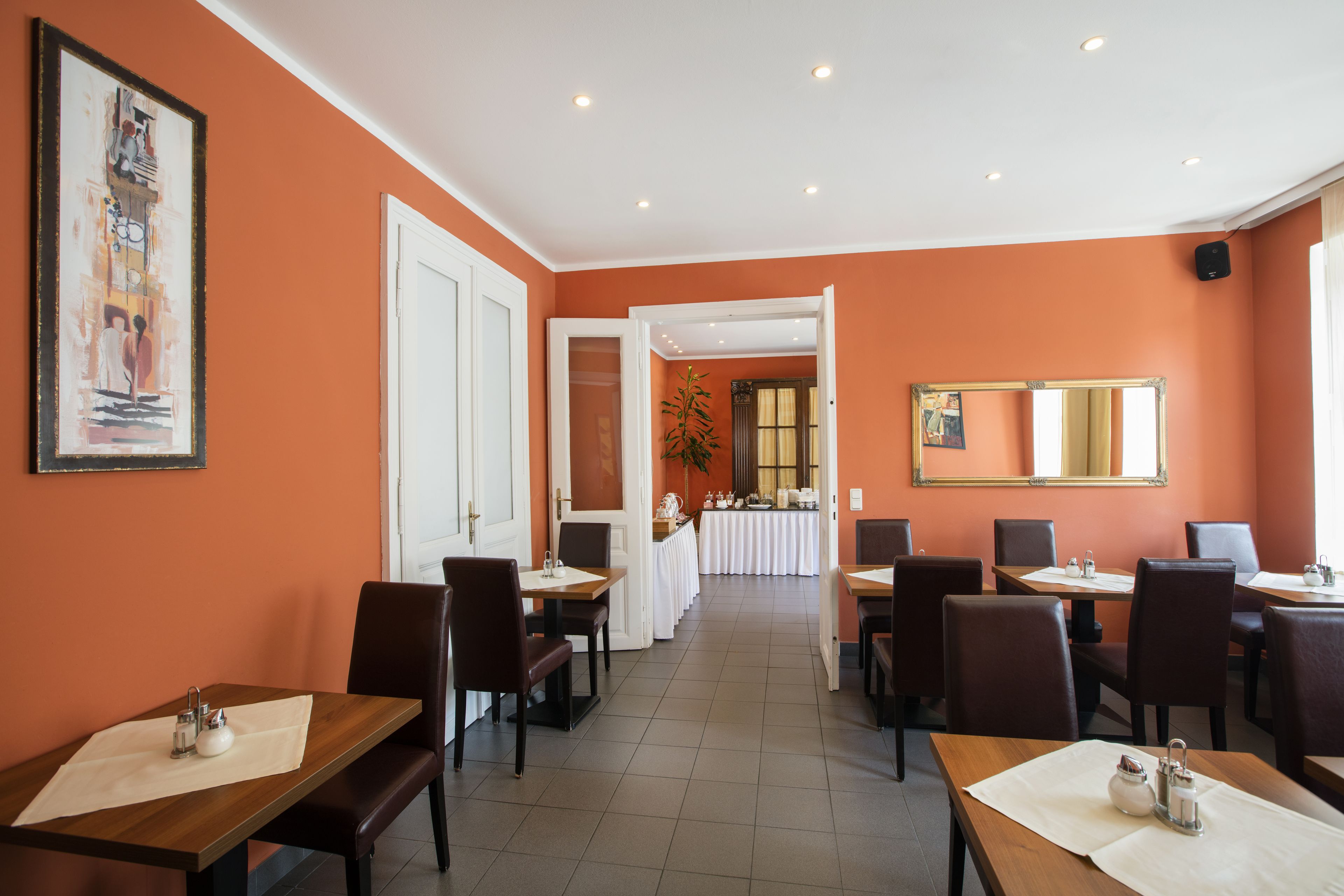 Un restaurante con una barra larga y varias mesas, un cuadro grande en la pared, y vistas al salón comedor.