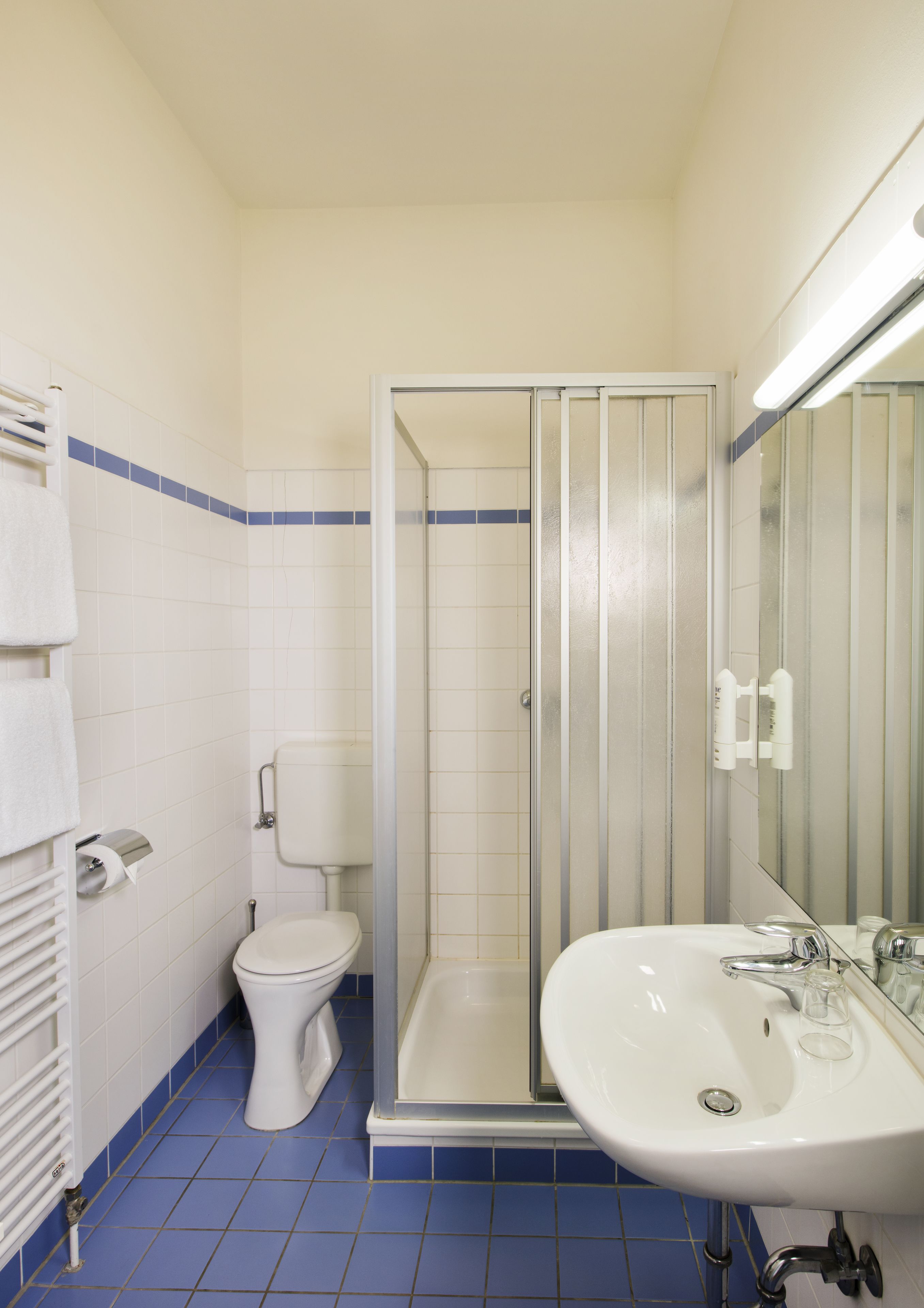 Un baño con inodoro, cabina de ducha y lavamanos.