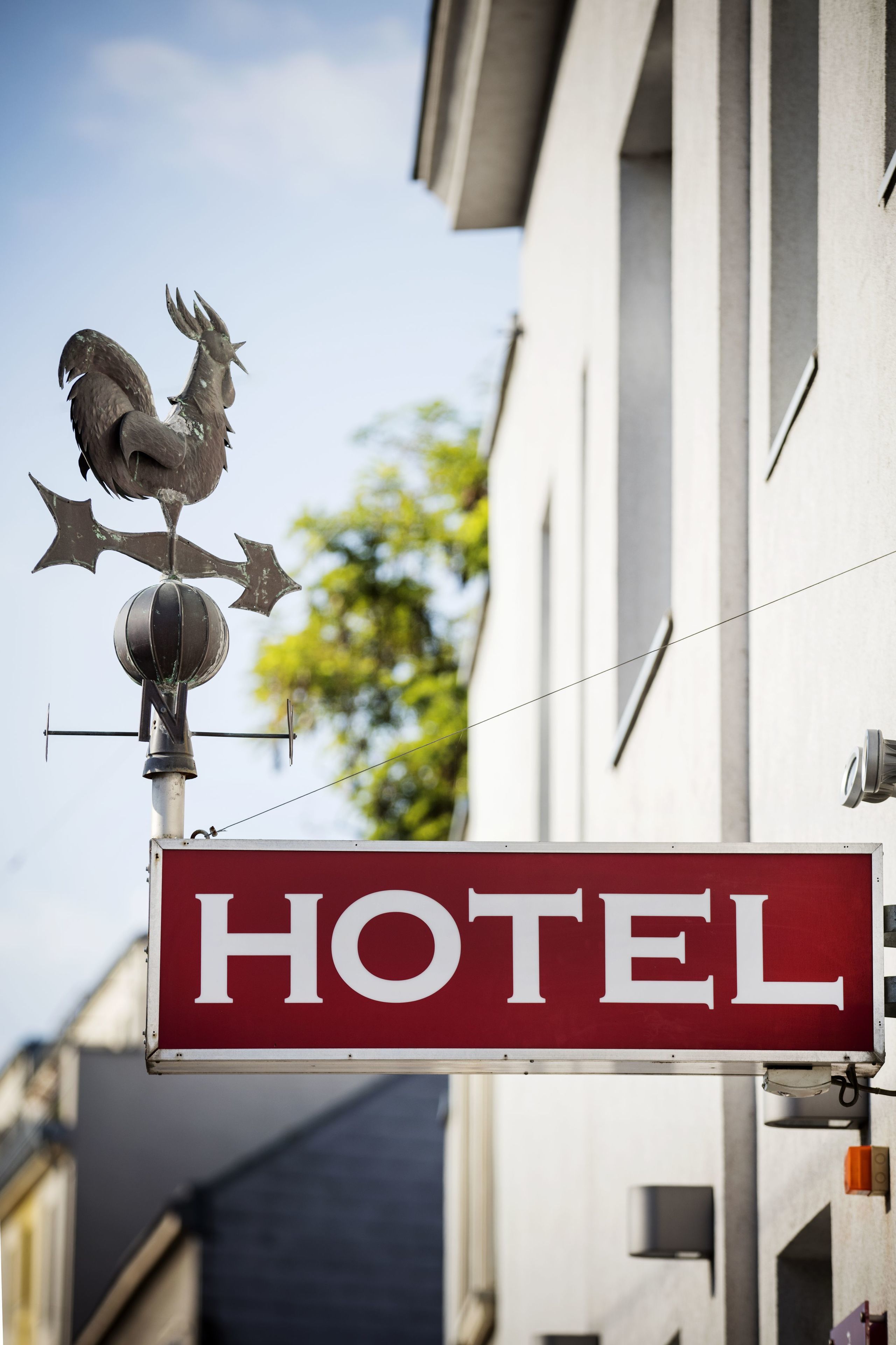 A hotel sign with a rooster weather vane.