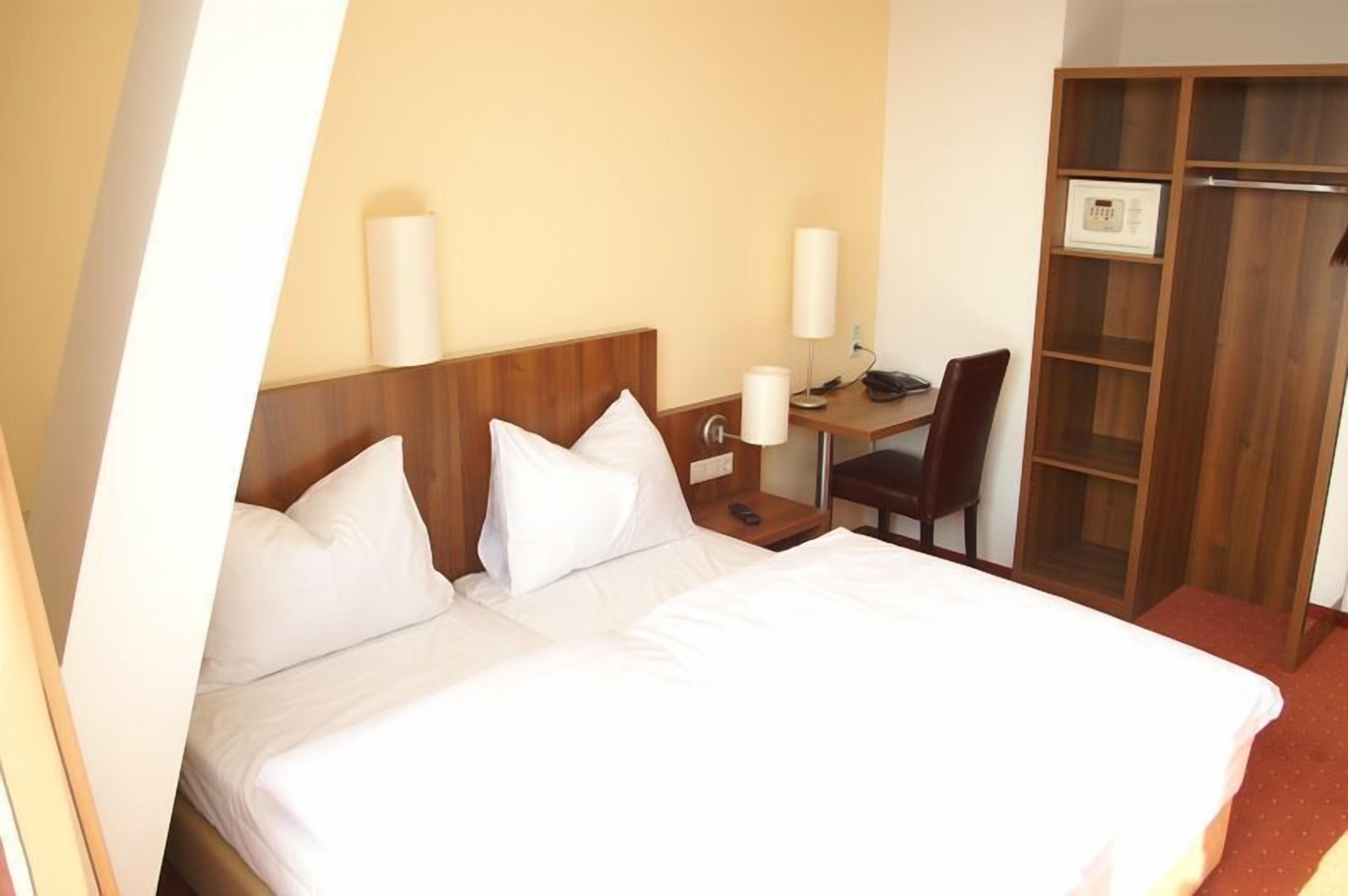 Una habitación de hotel con una cama grande, un escritorio y un armario.