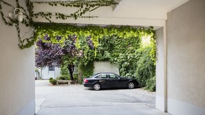 A parking garage with a car parked in the middle. There are plants growing on the walls and a bench in the background. - Hahn Hotel Vienna City (Vienna)
