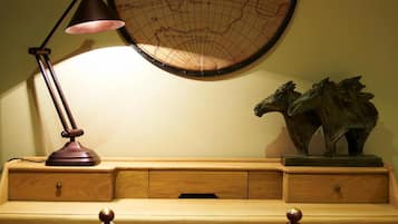 A wooden desk with a globe, a lamp, and a horse sculpture.