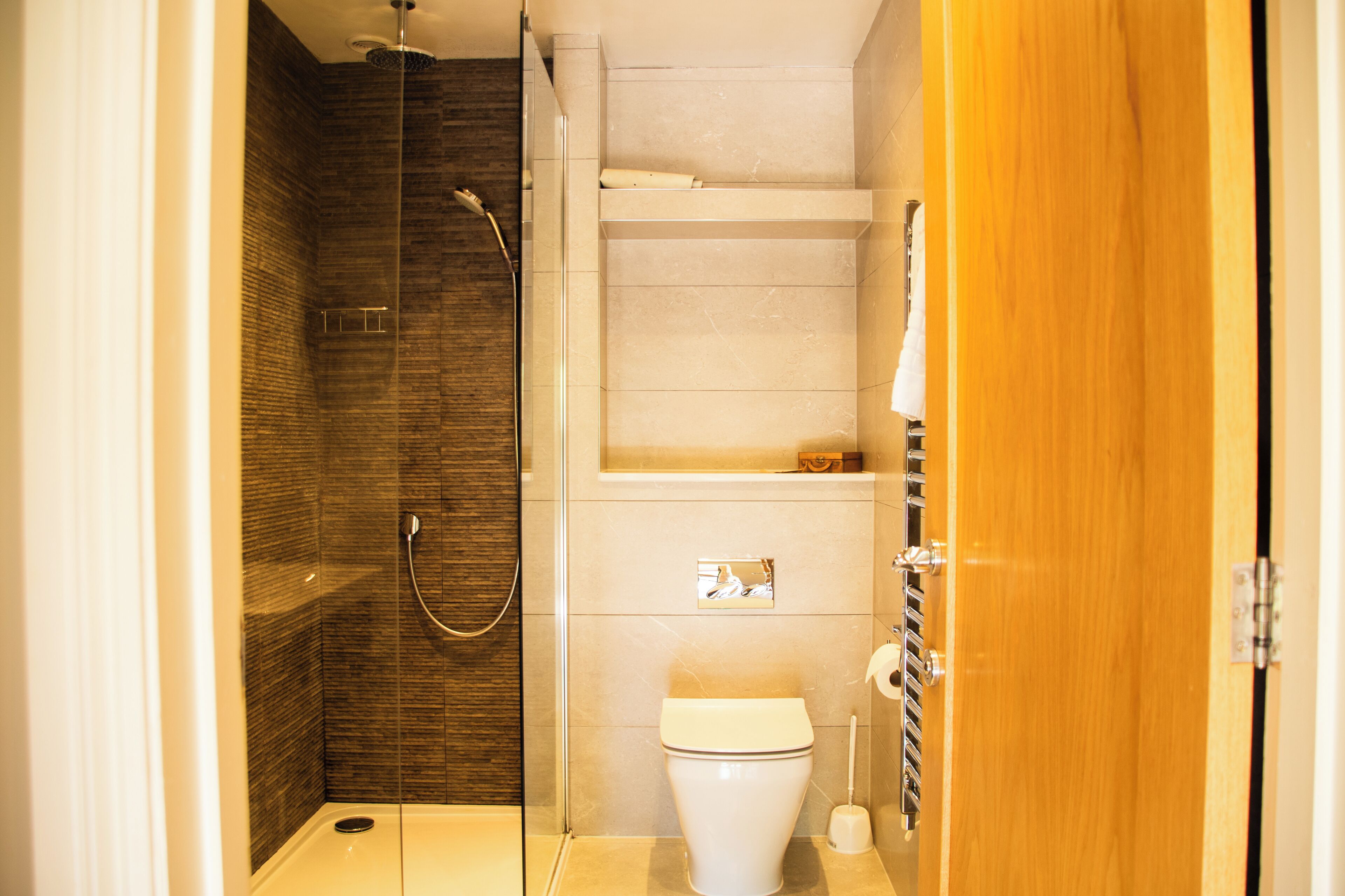 Un baño pequeño con ducha, inodoro y puerta de madera.