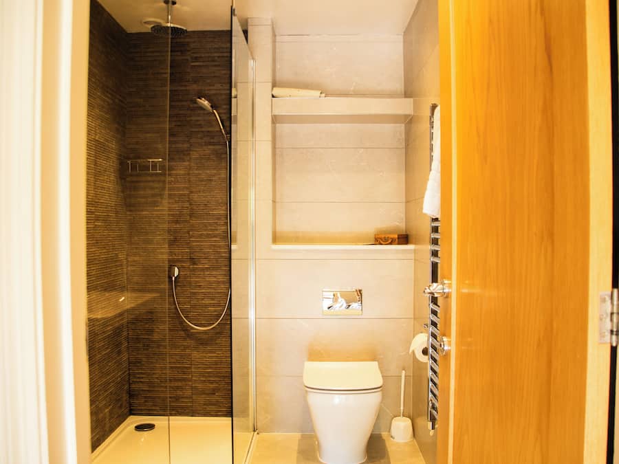 Une petite salle de bain comprenant une douche, des toilettes et une porte en bois.