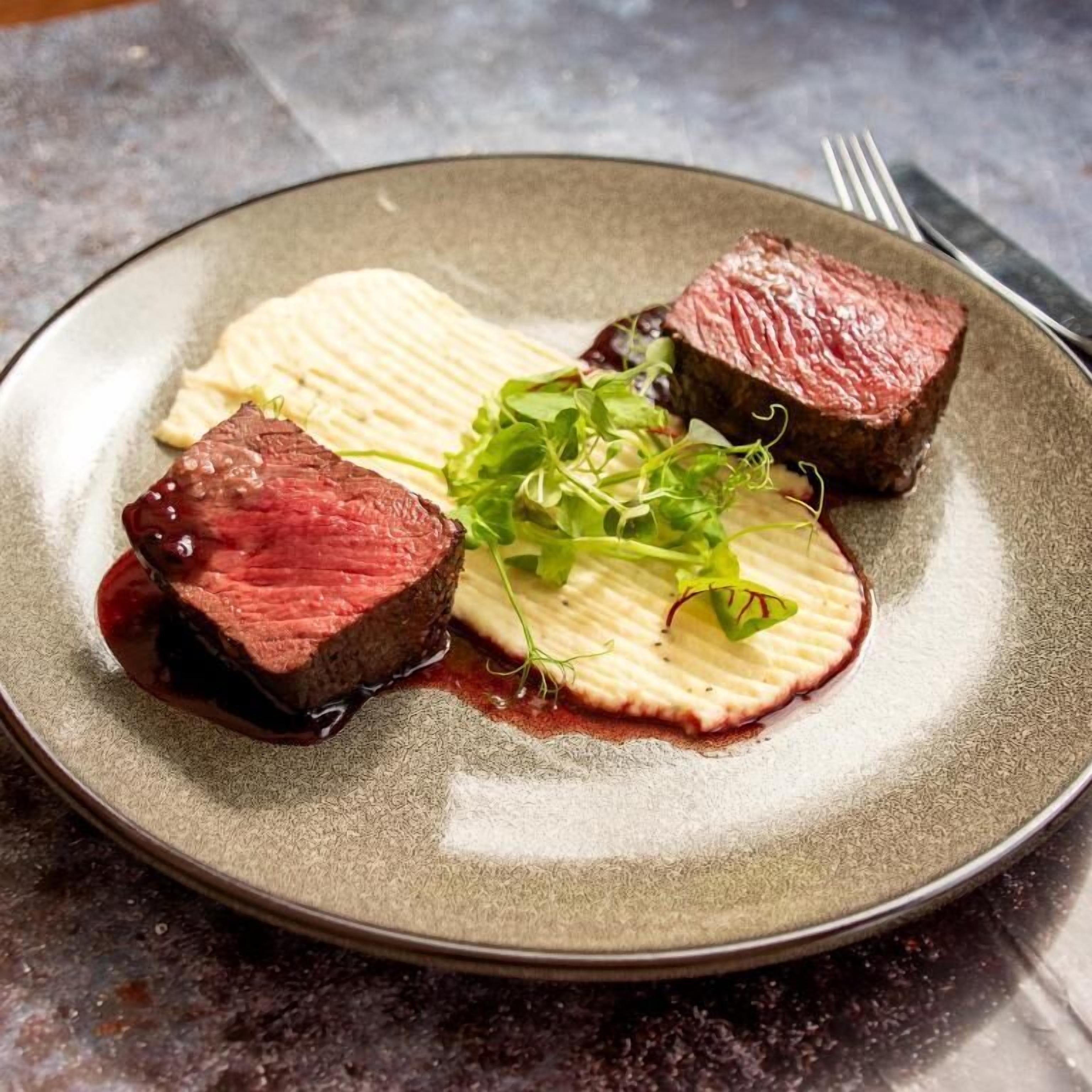 A plate with a steak and a slice of potato.