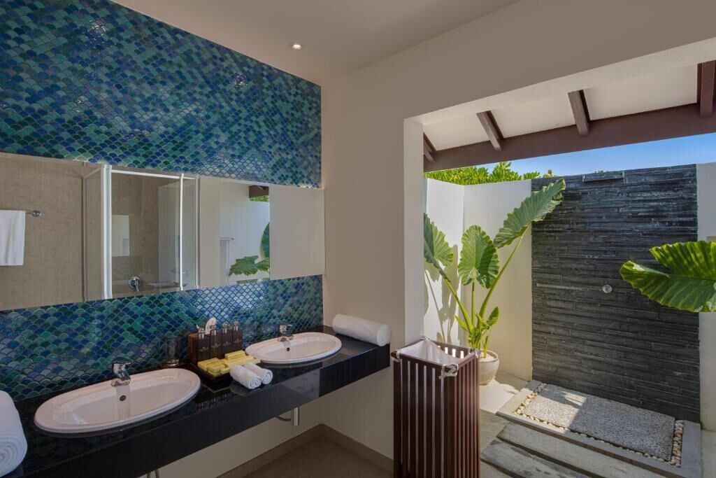 Un baño con dos lavabos, un espejo grande y una planta en maceta.