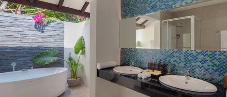 A modern bathroom with two sinks, a large bathtub, and a tiled backsplash.