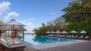 Una piscina al aire libre, sombrillas, sillones reclinables de piscina
