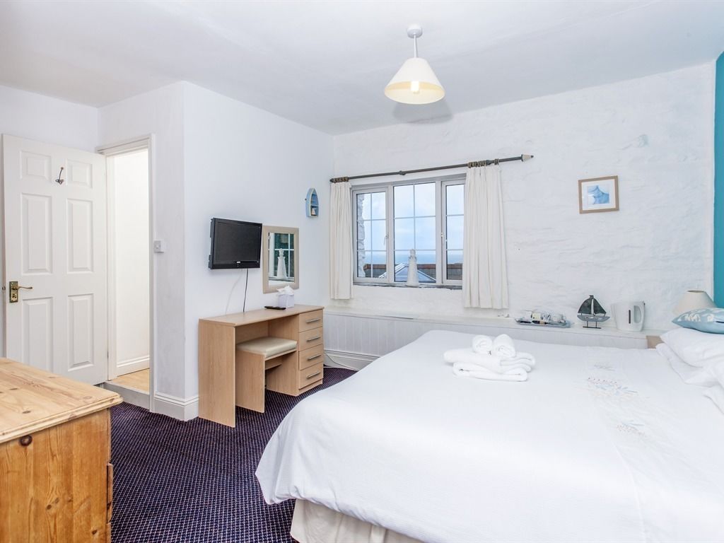 Een hotelkamer met een groot bed, een bureau met stoel, een televisie en een raam met gordijnen.