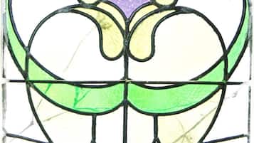 A stained glass window with a symmetrical design featuring green, yellow, and purple colors.