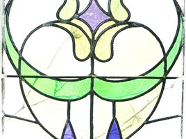A stained glass window with a symmetrical design featuring green, yellow, and purple colors.
