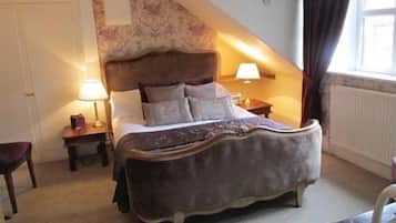 Une chambre à coucher avec un grand lit, une table de chevet, une lampe et une fenêtre avec des rideaux.