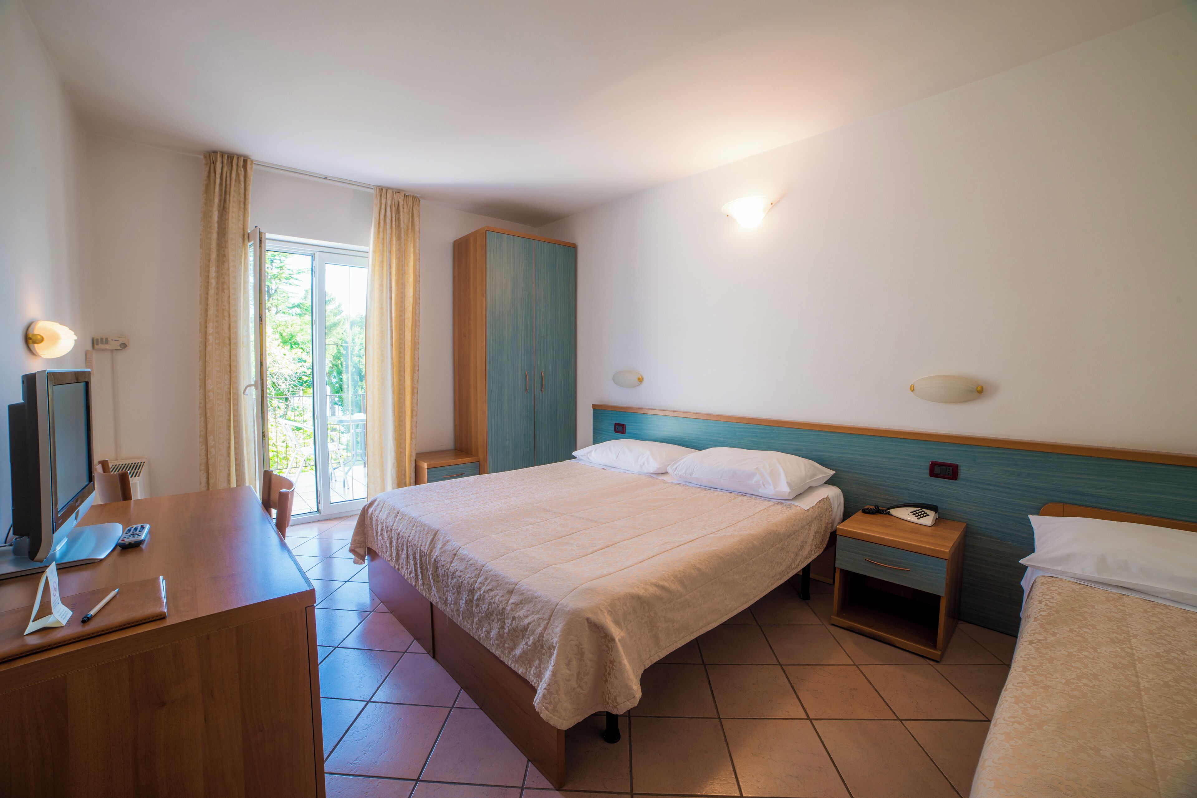 Une chambre d’hôtel équipée d’un lit, d’une table de chevet, d’un bureau et d’une télévision.