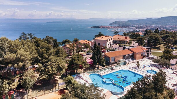 Ein Resort mit einem großen Schwimmbad, mehreren Gebäuden und Blick auf das Meer.