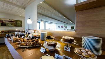 A buffet area with various food items, including pastries, cakes, and a yogurt station.