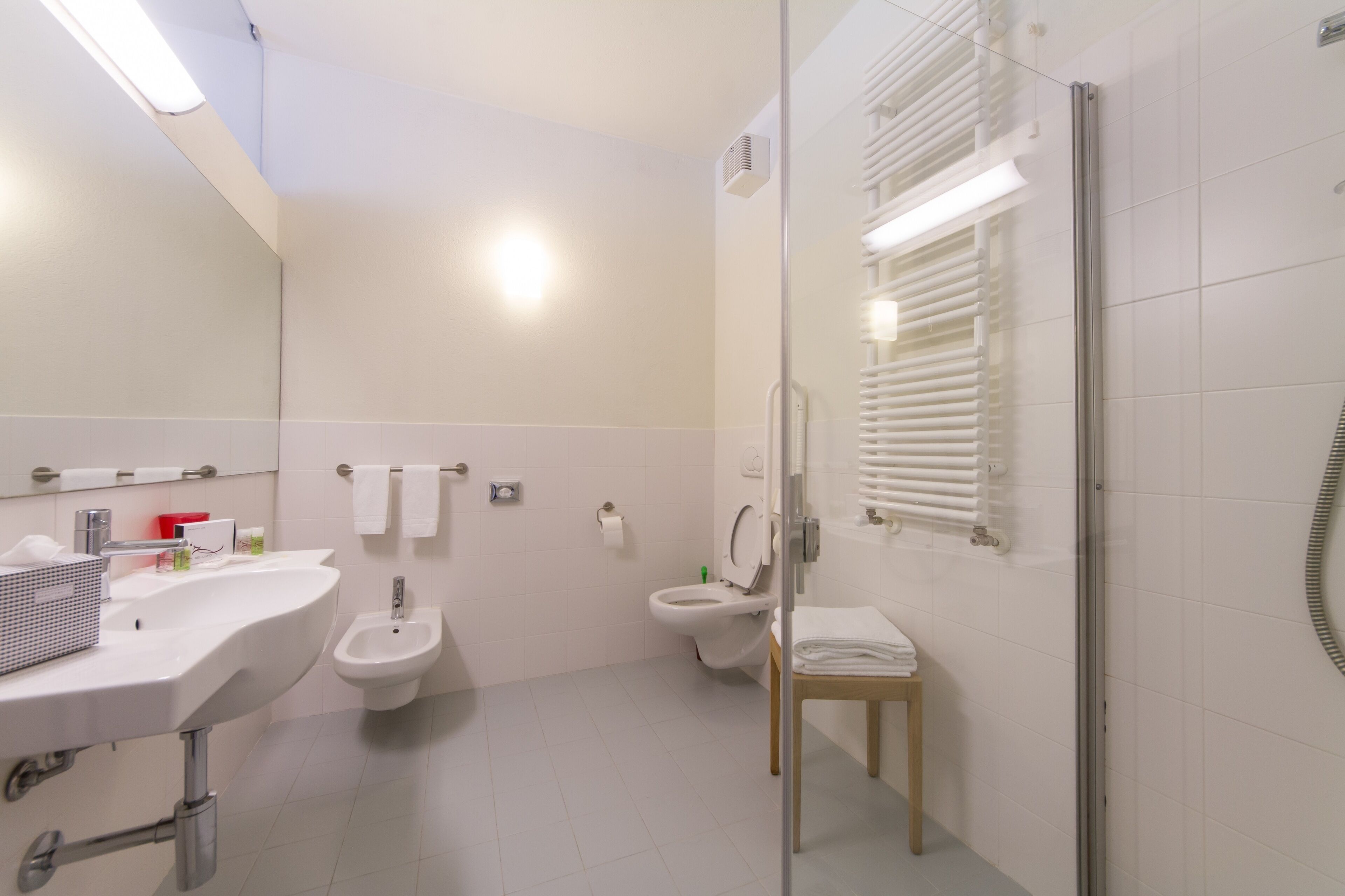 A modern bathroom with a sink, bidet, toilet, and glass shower enclosure.
