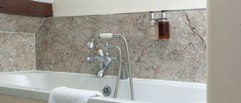 Un baño con bañera, ducha y una toalla colgada en la pared.