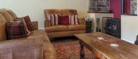 A cozy living room with leather sofas, a wooden coffee table, and a fireplace.