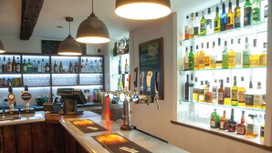 A bar with multiple taps, shelves of bottles, and a menu board. - The Dragon Hotel (Montgomery)
